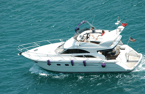 Bright white sedan bridge boat motoring across the ocean.